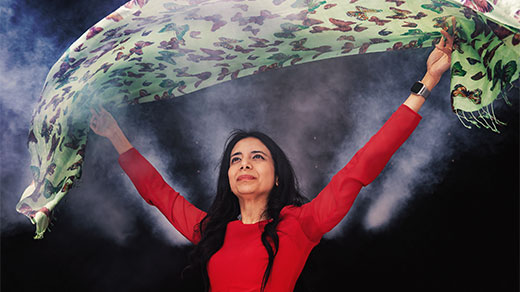 Anima Anandkumar in a red dress holds a green cloth over her head