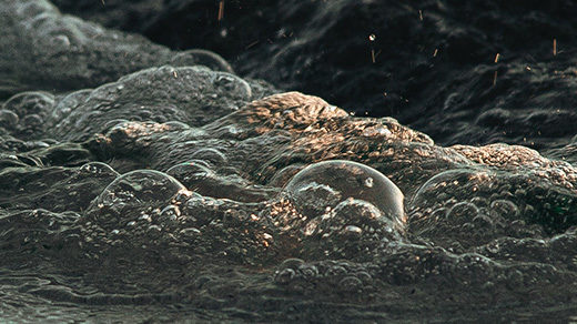 Close-up of water swirling among rocks at the sea’s edge.